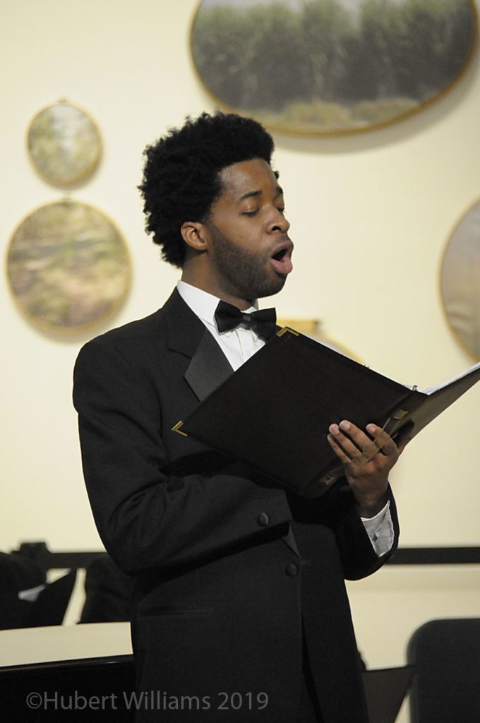 Photo of a man holding booklet and singing